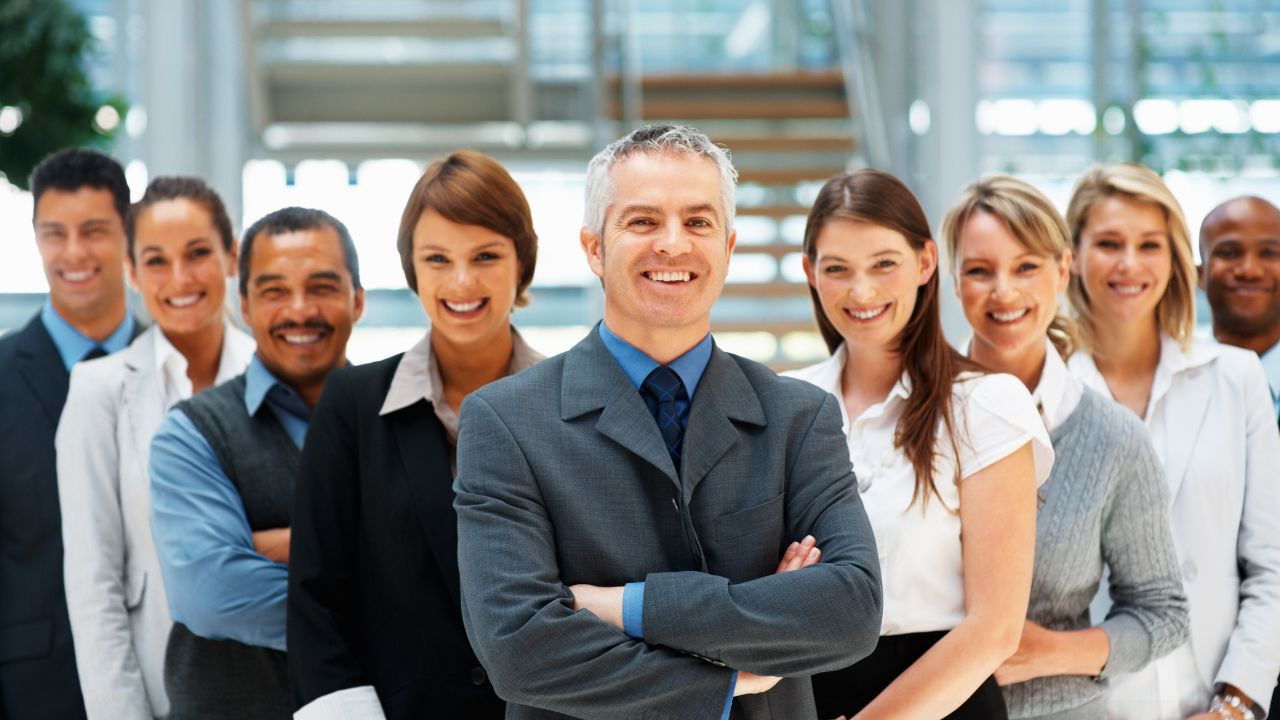 A diverse group of business leaders standing together in a bright atrium.
